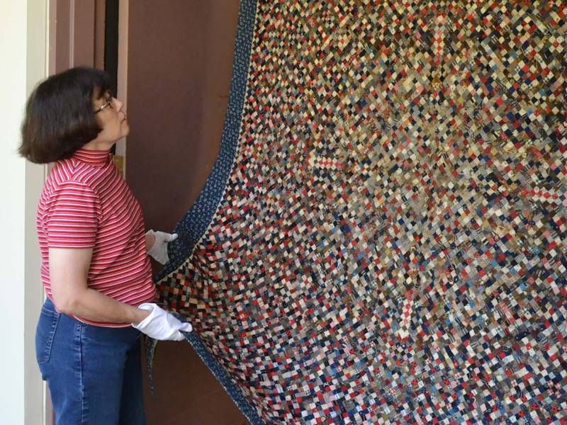 Sandy Staebell Inspects Postage Stamp Quilt